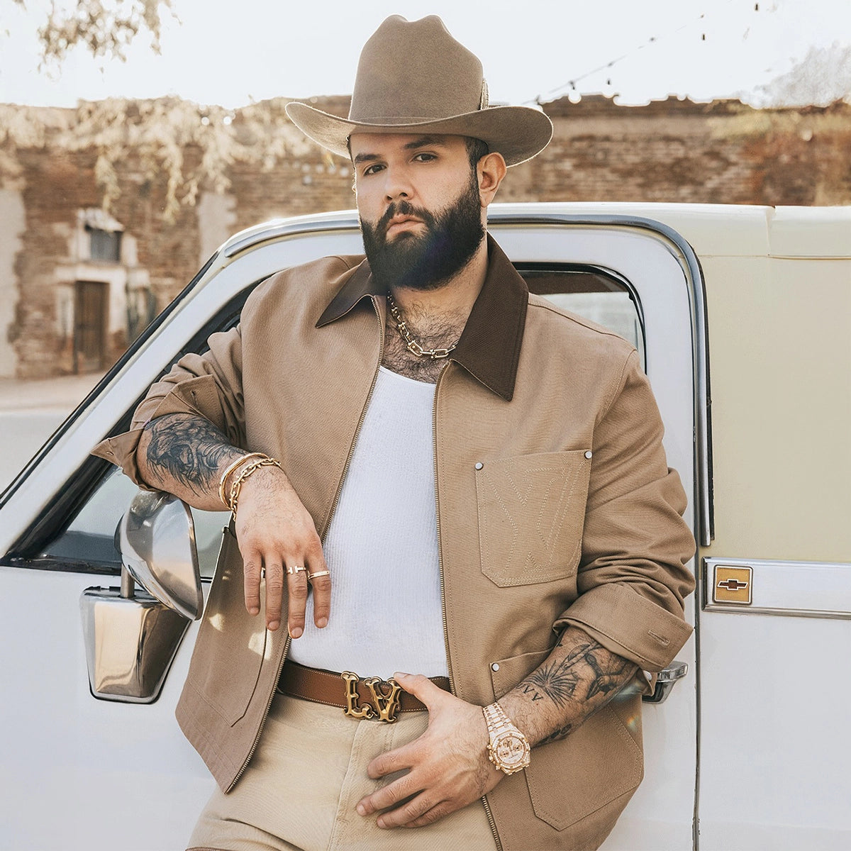 Carin Leon wearing tejana hat and jacket leaning in a truck.