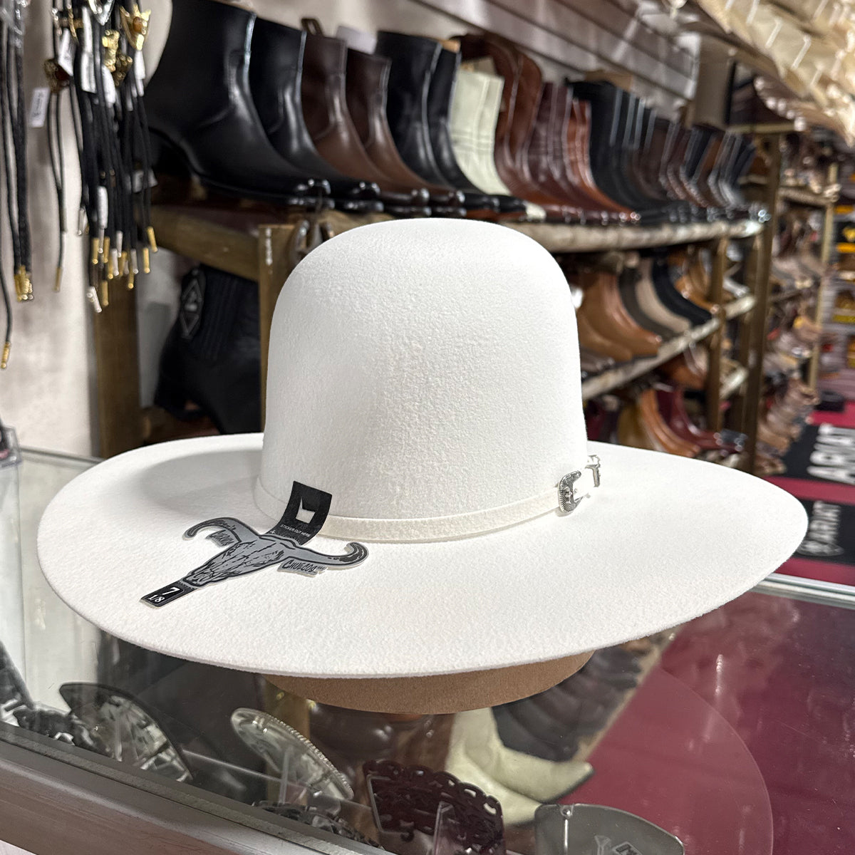 A white open crown cowboy hat displayed on a stand inside a western store.