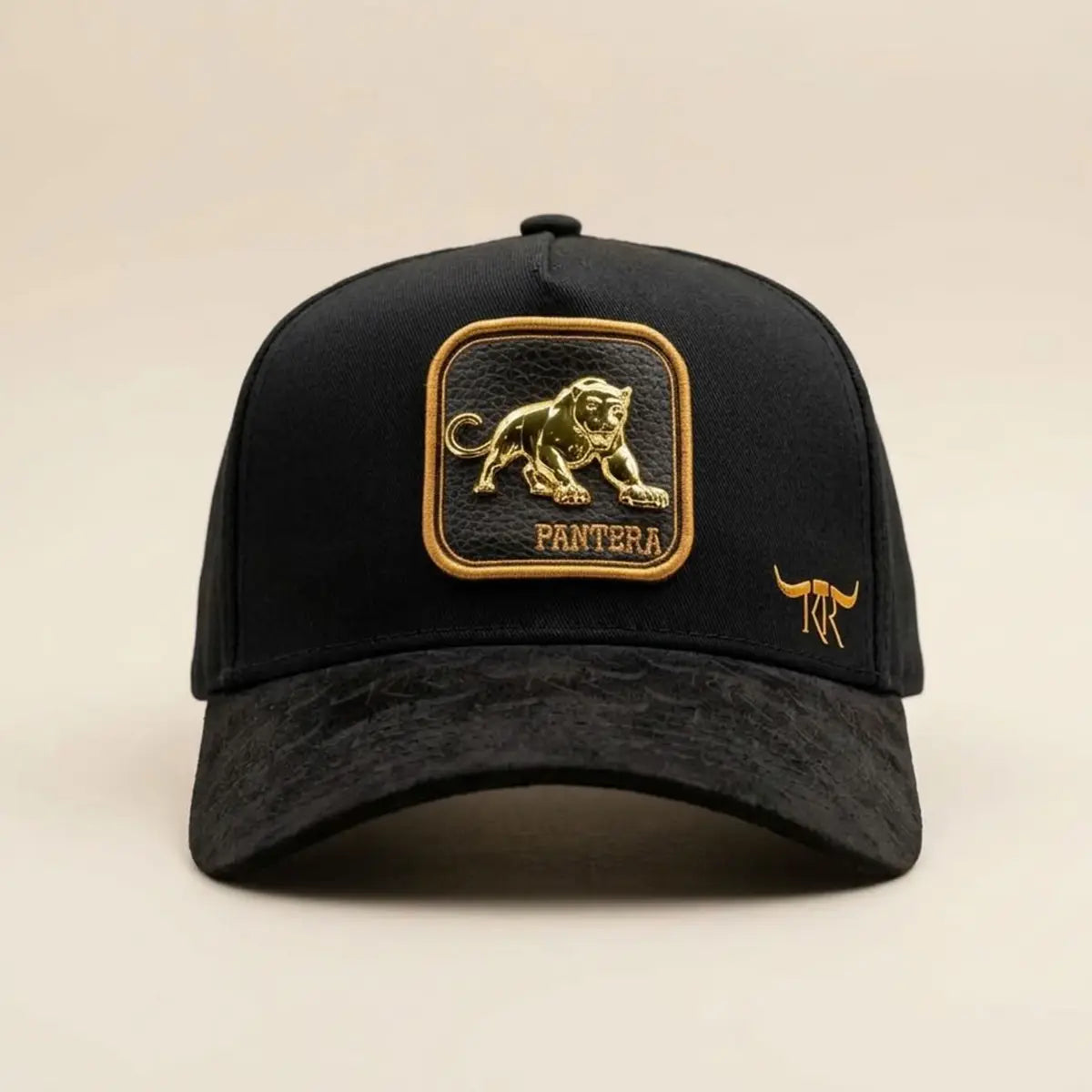 Straight-on front studio view of the King Ranch "Pantera" black snapback cap showing the metallic gold panther patch, textured suede visor, and gold longhorn logo.