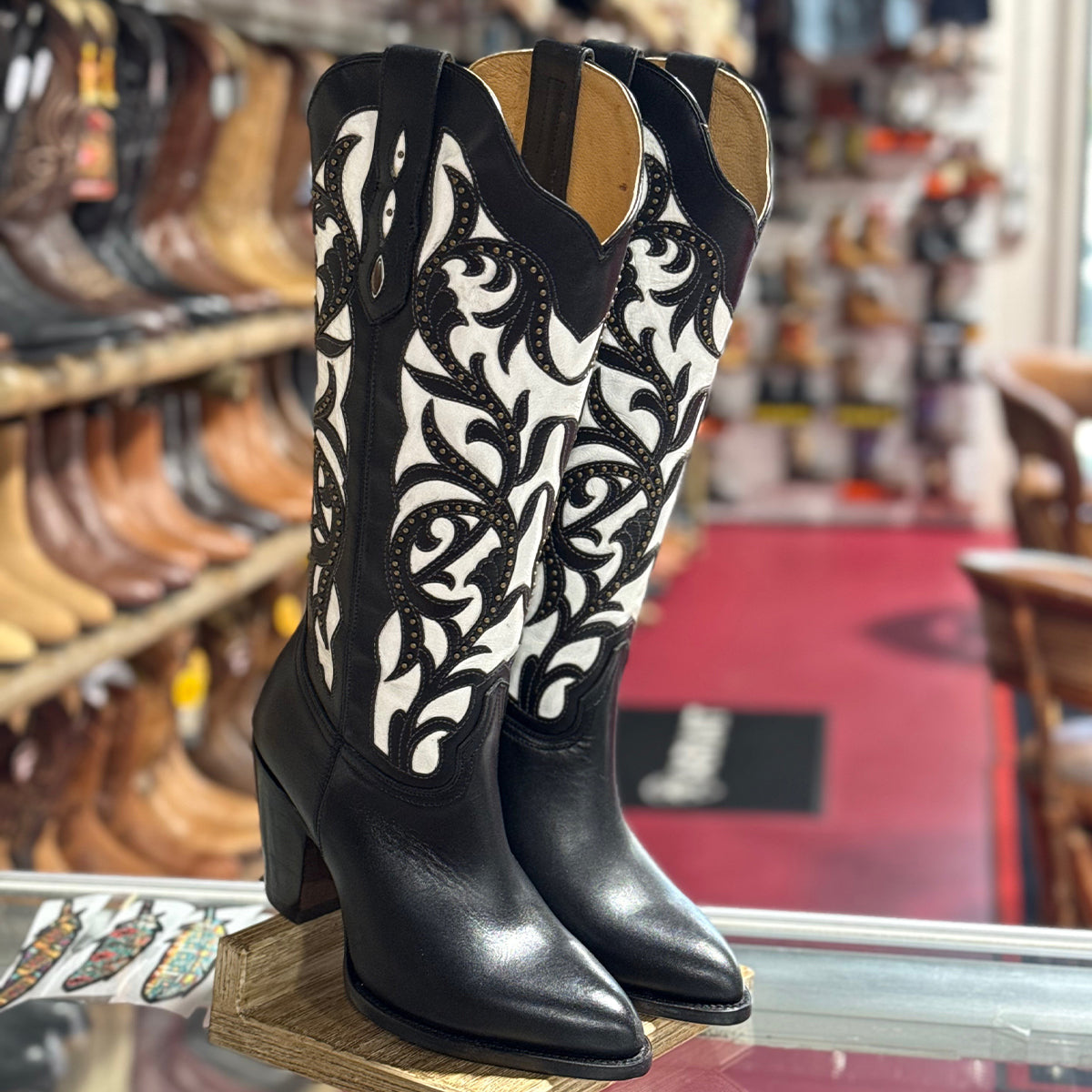 Rio Grande Isabela women's black and white leather cowgirl boots with high heels, sharp snip toes, black botanical scroll overlays with metallic brass studs, and pull straps.