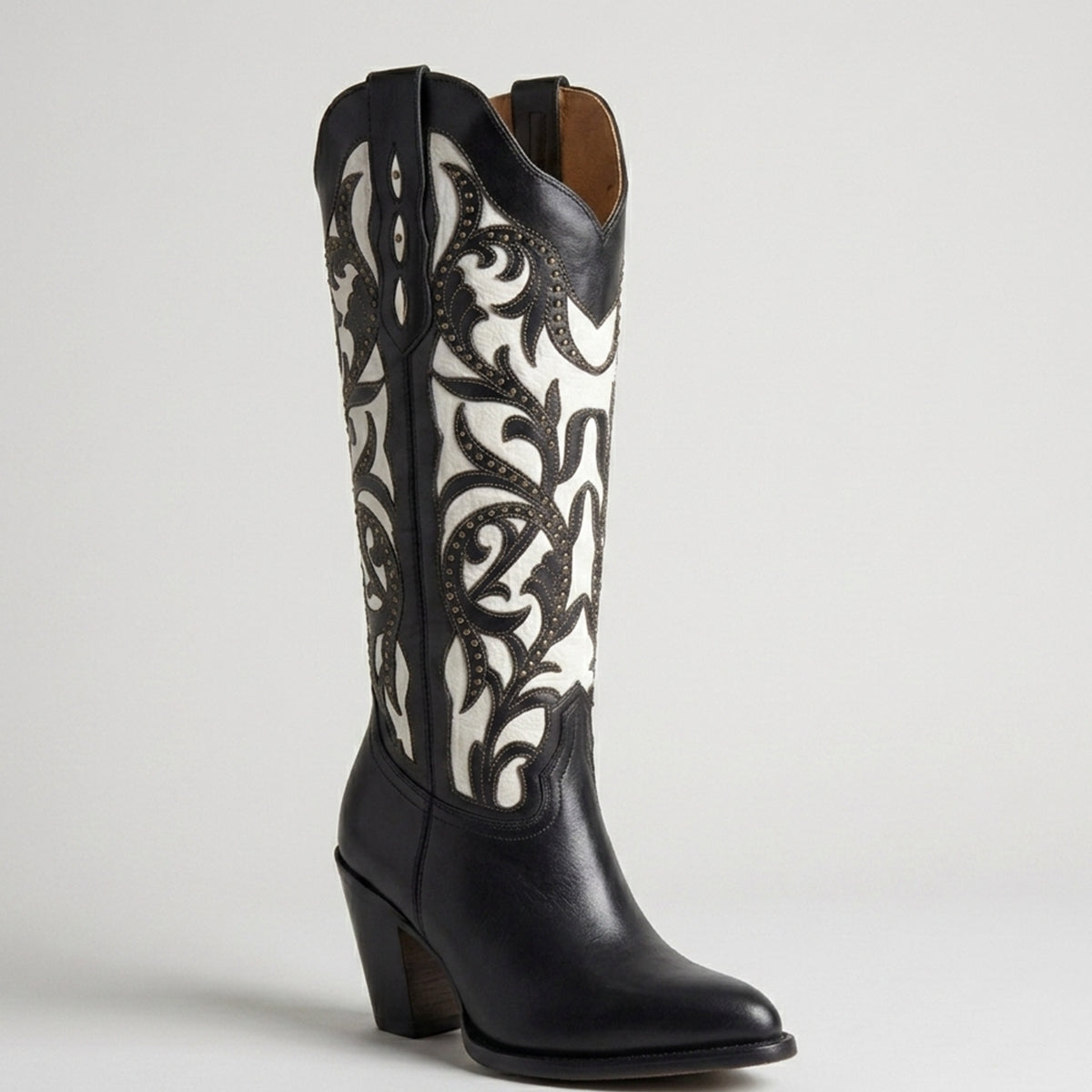 Rio Grande Isabela women's black and white leather western boot featuring intricate black floral cutouts over white leather, brass studs, and a 3-inch heel.