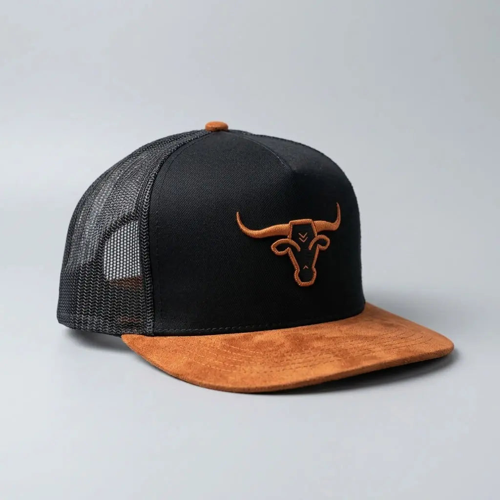 Three-quarter studio view of the Rodeo Bully black trucker cap displaying the brown suede visor, embroidered bull head logo, and black mesh back.