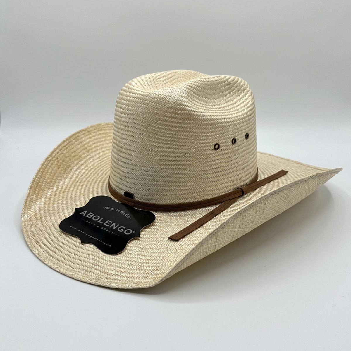 A woven Minnick straw cowboy hat in a light beige color, featuring a brown leather band with a brown ribbon and a black 'ABOLENGO' brand tag on the brim, set against a plain light gray background.