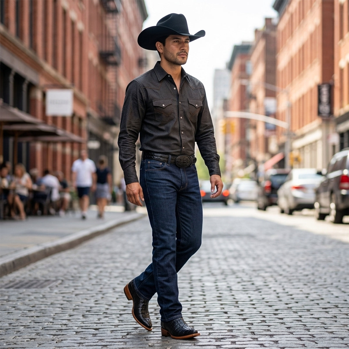 Model wearing men's black crocodile print pointed toe cowboy boots with dark jeans, black Western shirt, black belt, and black felt cowboy hat.