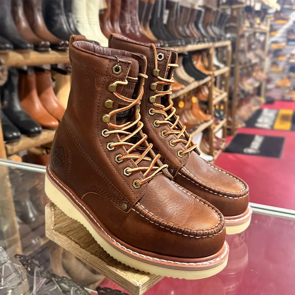 High-angle retail display view of the Work Zone 8-inch mocc steel toe work boots sitting on a glass counter inside a boot store.