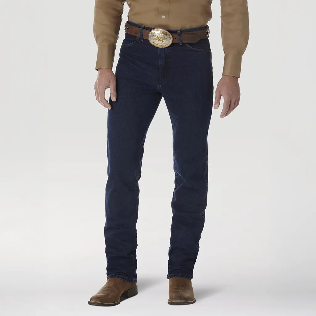 Front studio view of a model wearing Wrangler Men's 0936DSD Dark Stone Cowboy Cut Slim Fit jeans showing the high waist, trophy belt buckle, and dark indigo denim tone.