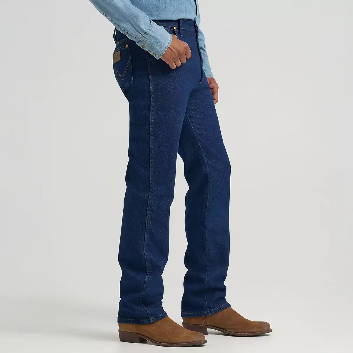 Side profile view of a man wearing Wrangler navy stretch slim fit jeans paired with a denim Western shirt and brown boots.