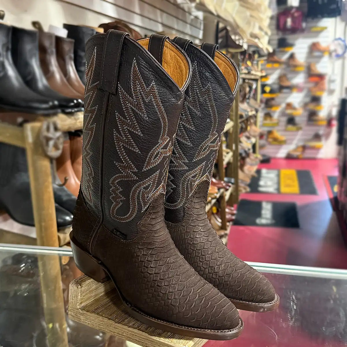 Three-quarter view of a pair of men's brown matte python snake print western boots with a classic round toe and matching embroidered leather upper.