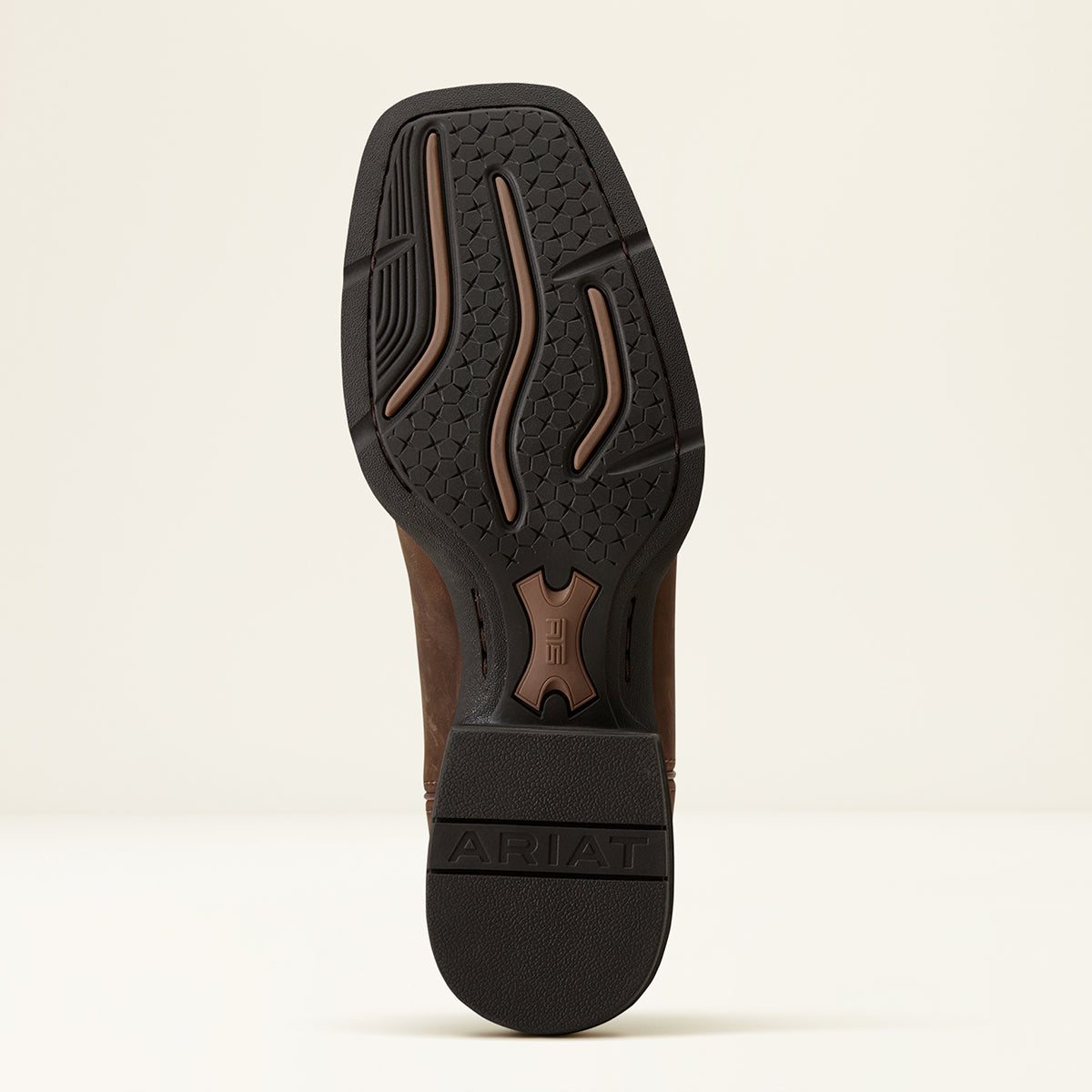 The outsole of a brown leather boot with a black treaded rubber base, shown from a top-down view on a light beige background. The brand name 'ARIAT' is embossed on the heel.