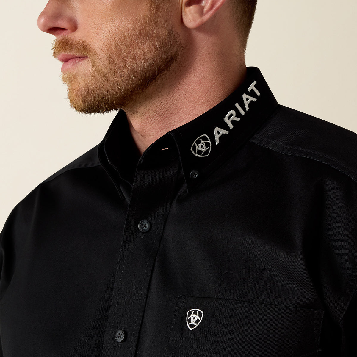 Close-up views of a man wearing the Ariat Men's Black Team Logo long sleeve twill shirt with collar embroidery.
