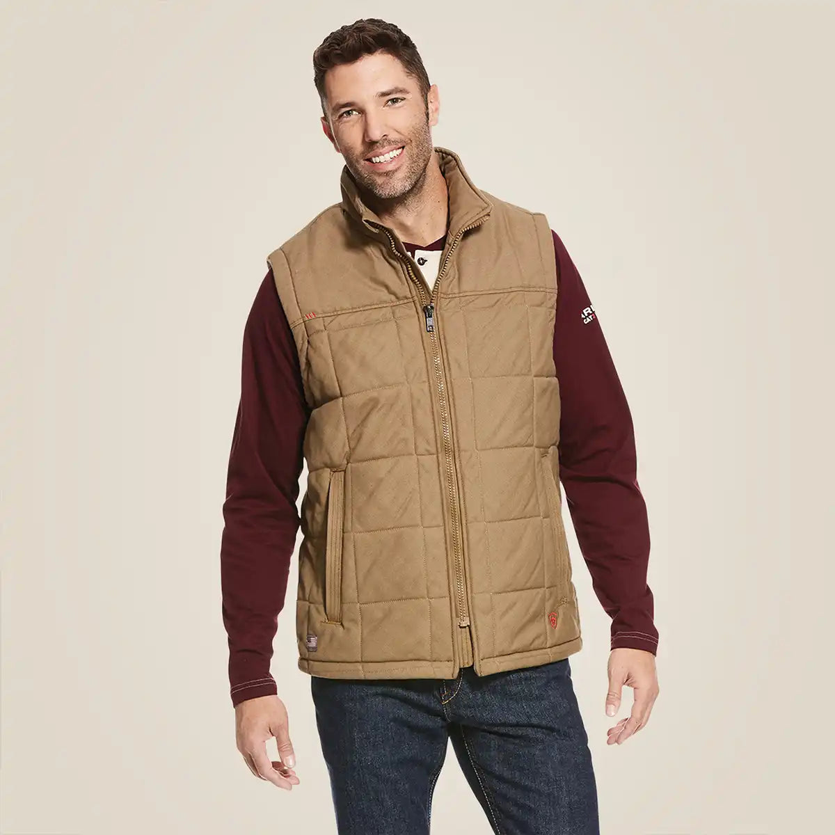 Front view of a man wearing the Ariat Men's Field Khaki FR Crius insulated quilted canvas work vest over a long sleeve shirt.