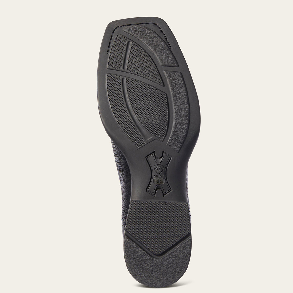 The black rubber outsole of Ariat boot., showing tread patterns and a central logo, photographed from a top-down view against a light beige background.