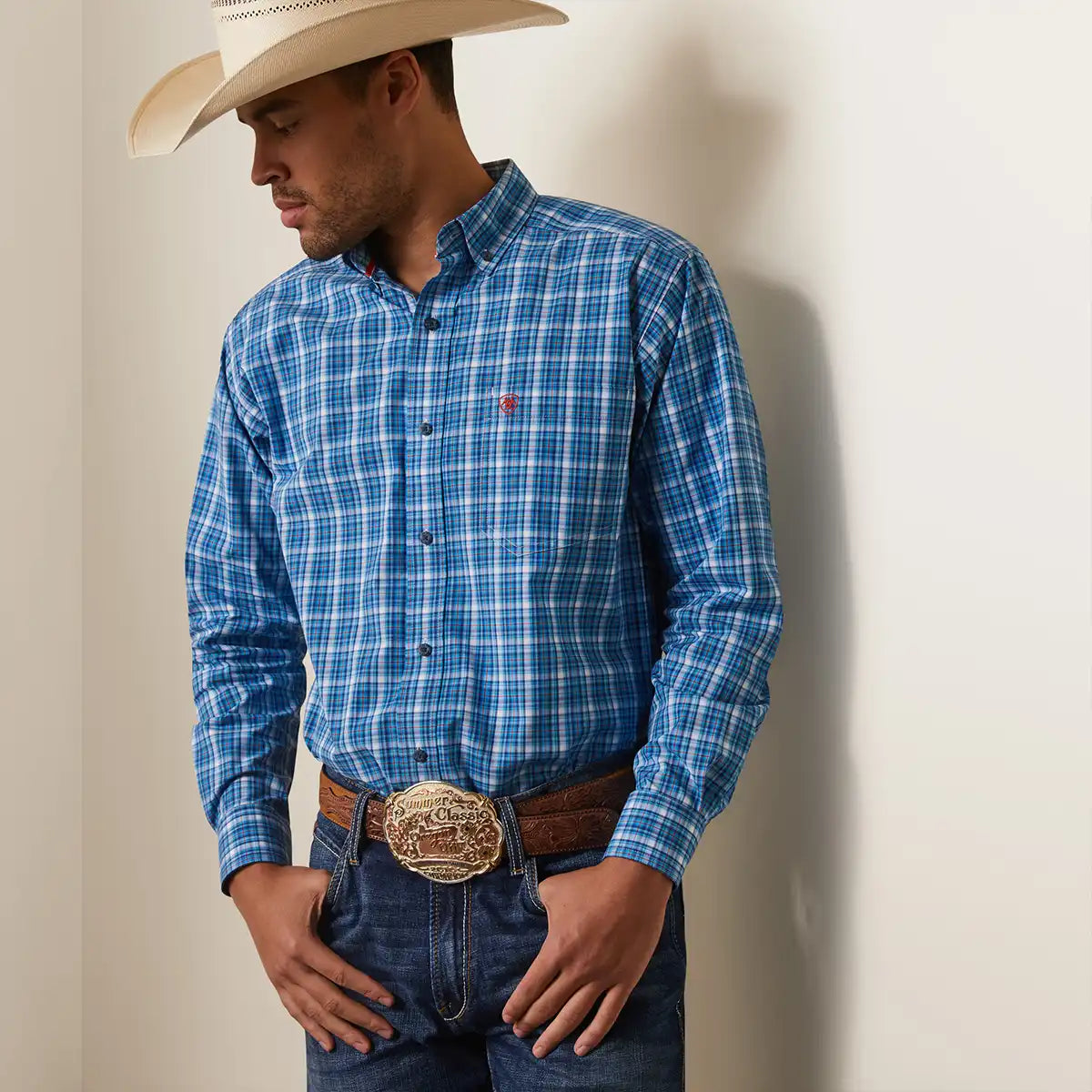 Front view of a man wearing the Ariat Men's Blue Pro Series Leyton blue and white plaid long sleeve button-down shirt with hat and belt.
