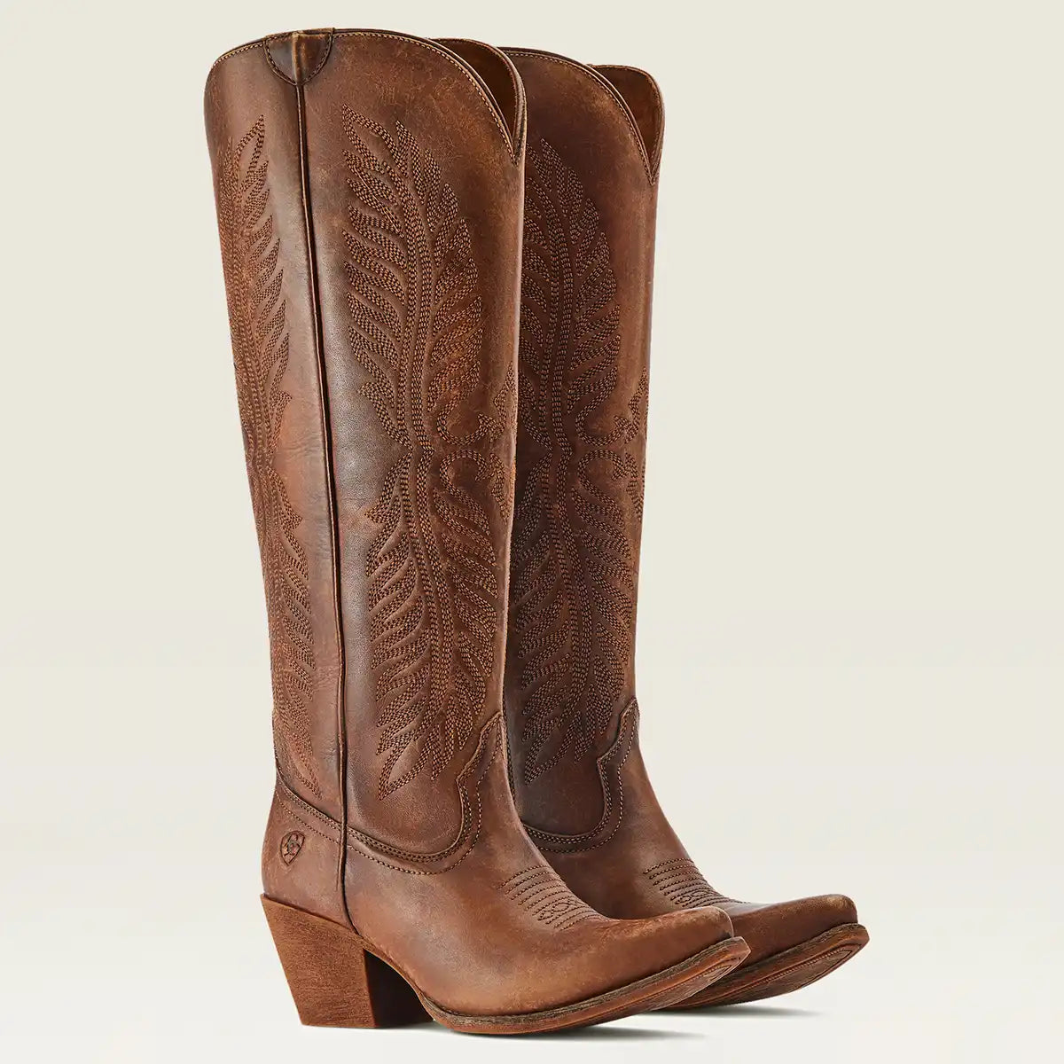 A pair of Ariat women's brown leather knee-high cowboy boots with decorative tooling and stitching, shown against a plain light beige background.