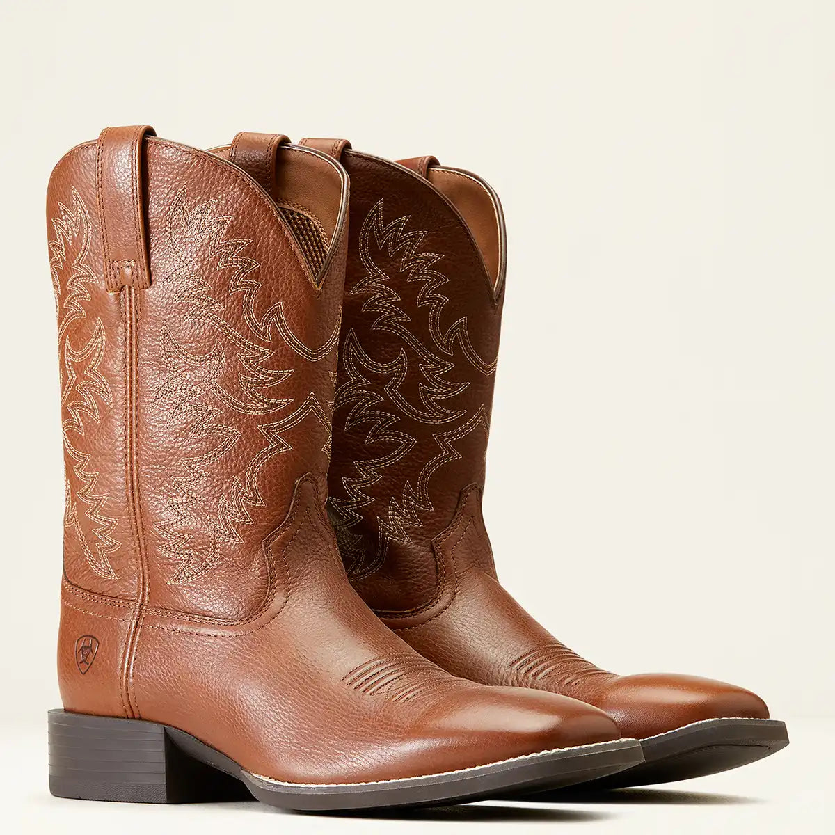 A pair of Ariat brown leather cowboy boots with decorative western stitching, shown on a clean off-white background.