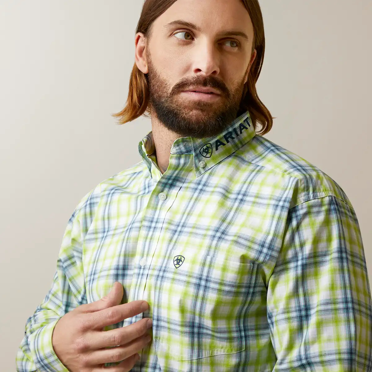 Man wearing a green and blue plaid shirt with ARIAT logo.
