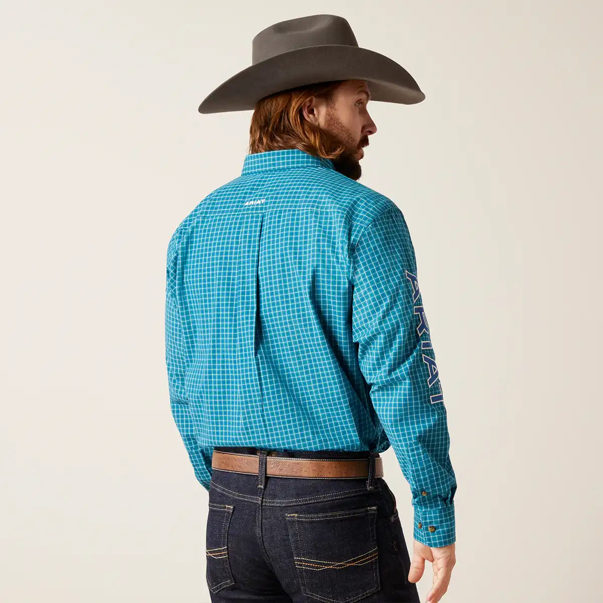 Man wearing a blue checkered shirt and cowboy hat on a plain background.