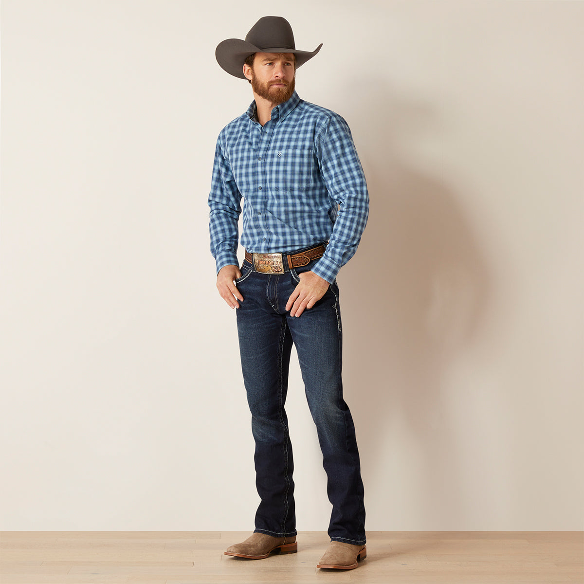 Full-body view of a man wearing the Ariat Men's Pro Series Gradison Sky Blue plaid long sleeve fitted button-down shirt with hat and jeans.