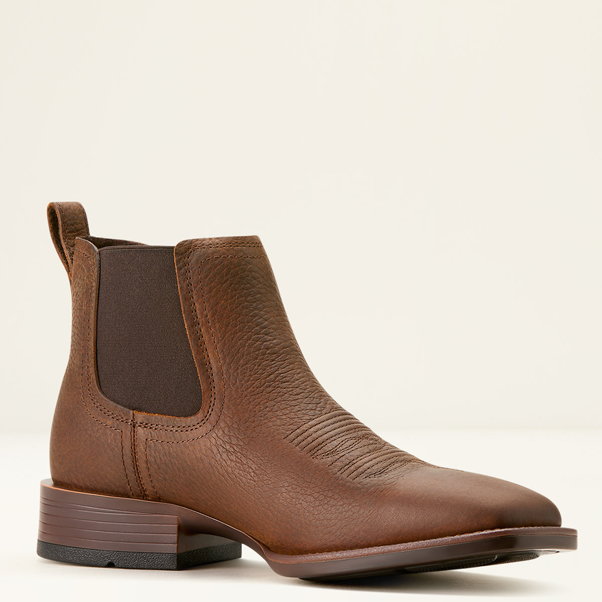 Ariat Men’s Booker Chelsea boot in Brown Oiled Rowdy pebbled leather featuring elastic side panels, front and rear pull tabs, and a square toe profile.