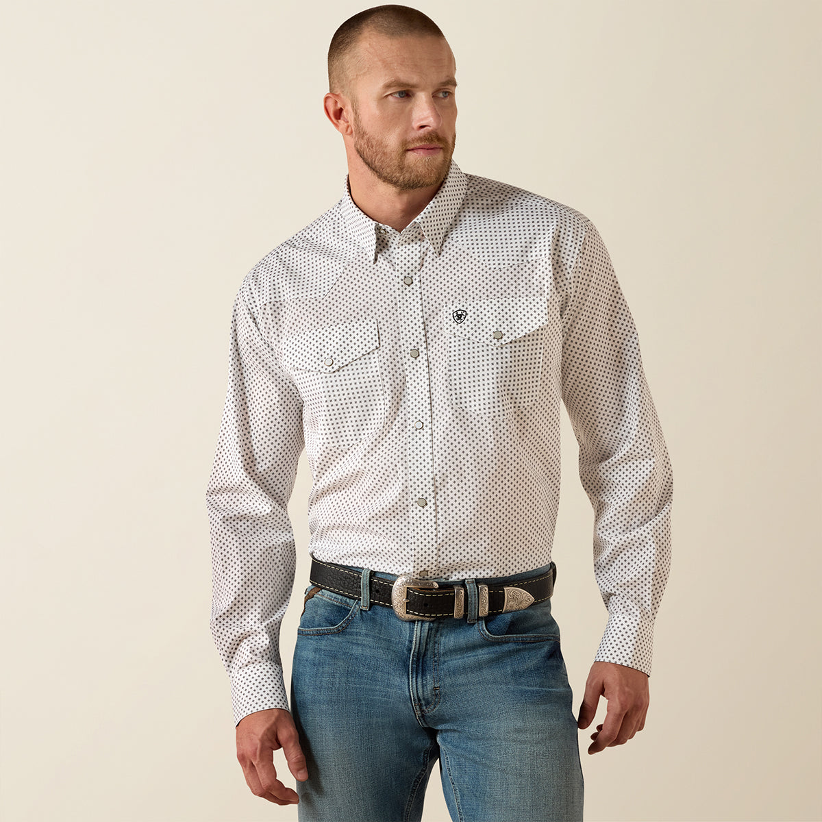 Front view of a man wearing the Ariat Men's White Anthony Wrinkle Free Classic Fit long sleeve Western pearl snap shirt with geometric micro-print.