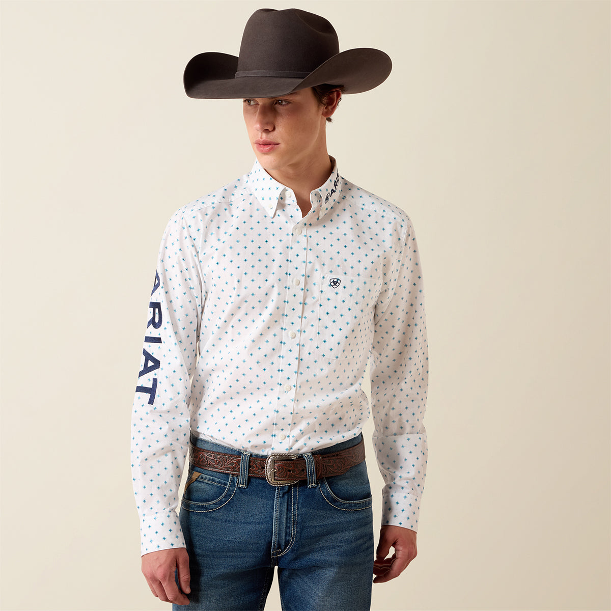 Front view of a man wearing the Ariat Men's Team Emory white printed long sleeve fitted shirt with cowboy hat and jeans.