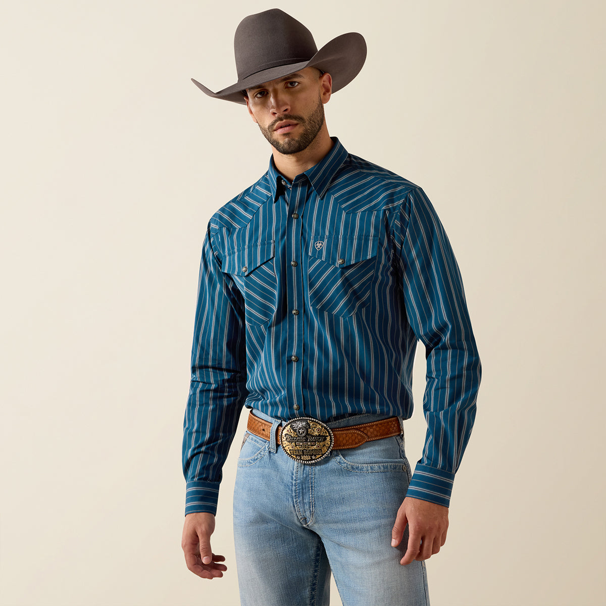 Front and full-body views of a man wearing the Ariat Men's Pro Series Wolfgang Sailor Blue vertical stripe long sleeve snap shirt with hat and belt.