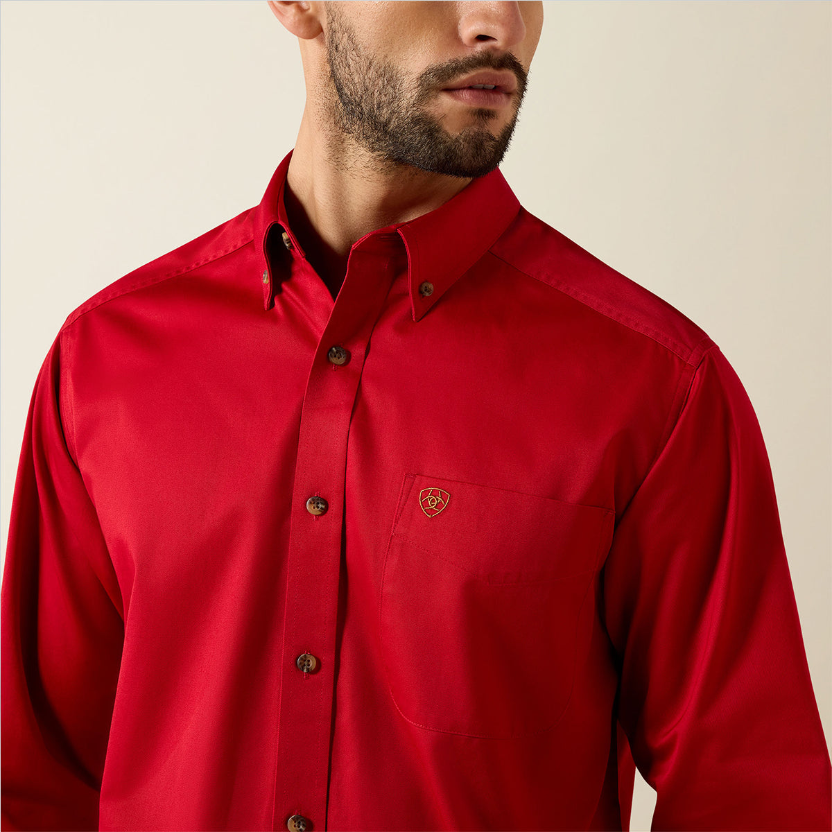 Close up views of a man wearing the Ariat Men's Solid Twill long sleeve button-down shirt in vivid Scarlet red with embroidered logos.