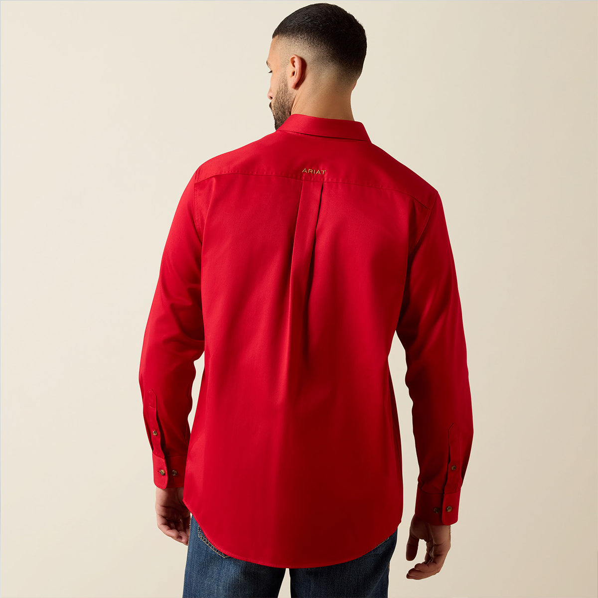 Back views of a man wearing the Ariat Men's Solid Twill long sleeve button-down shirt in vivid Scarlet red with embroidered logos.