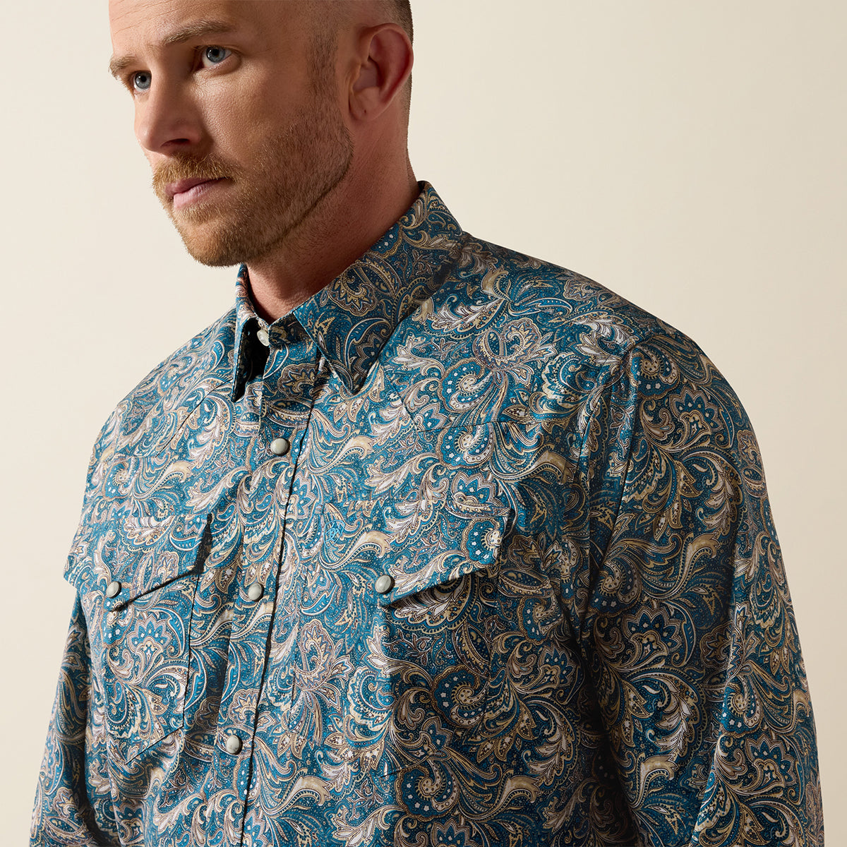 Close up views of a man wearing the Ariat Men's Cedric Blue Paisley print long sleeve Western snap shirt.