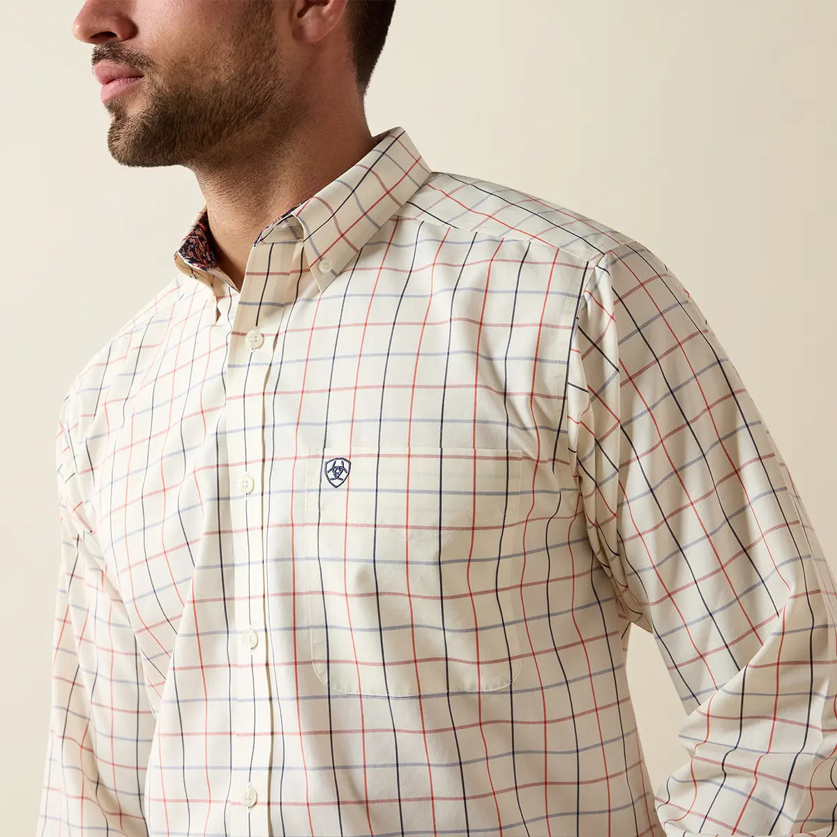 Close-up upper torso view of the Ariat Arctic Wolf windowpane shirt highlighting the button-down collar, chest pocket with logo, and red/navy plaid grid.