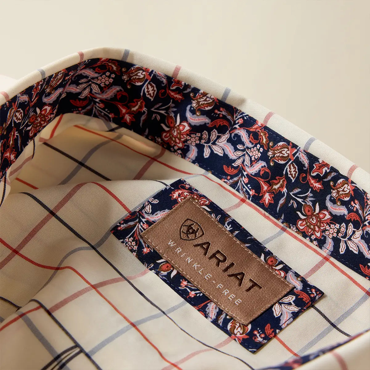 Close-up view of the inner collar of the Ariat shirt displaying the Wrinkle-Free label and dark floral neckband lining.