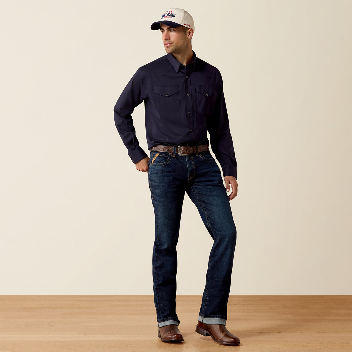 Front and full-body view of a man wearing the Ariat Men's Everything Navy long sleeve Western snap shirt with cap, jeans, and boots.
