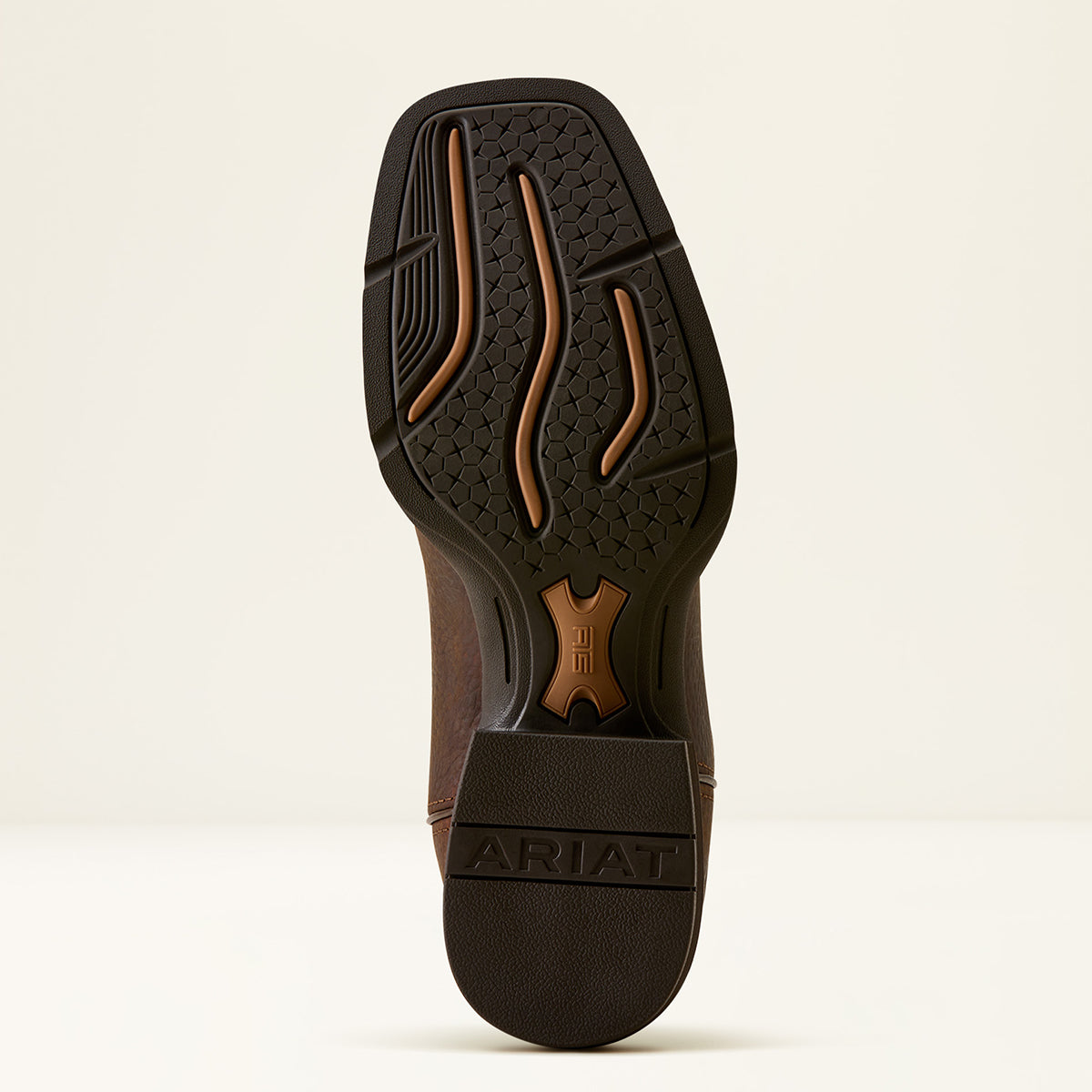 The outsole of an Ariat boot shown from a top-down view, featuring a dark brown textured tread with tan accents and the brand name 'ARIAT' embossed on the heel.