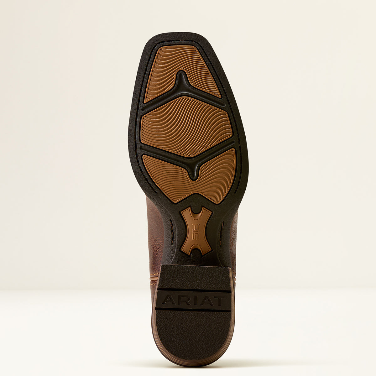 The outsole of a brown leather boot with a black treaded edge, showing the Ariat logo on the heel and a textured brown rubber sole, photographed against a clean off-white background.