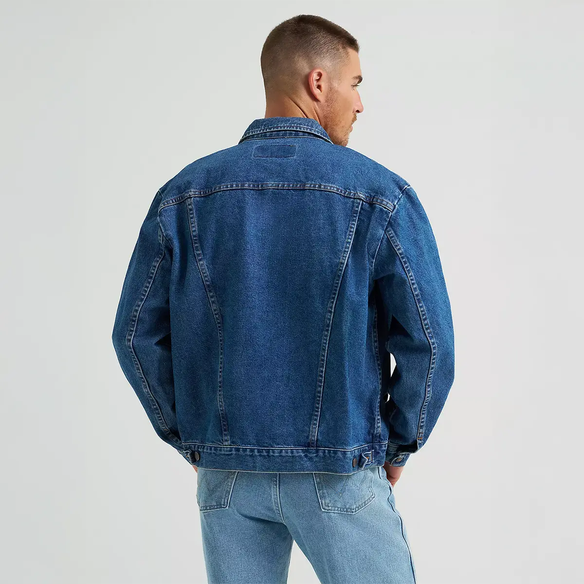 Rear view of the model showcasing the back seams, waist adjusters, and shoulder fit on the Wrangler Cowboy Cut denim jacket.