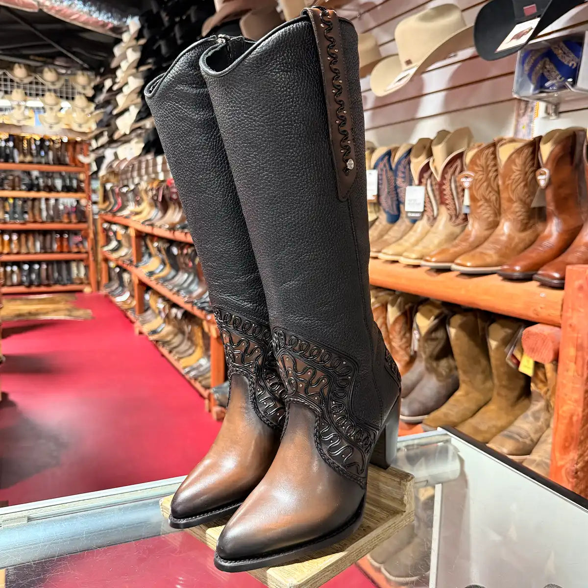Pair of Cuadra Women's chocolate leather boots with 2D organic embroidery and metallic studs displayed on a glass shelf.