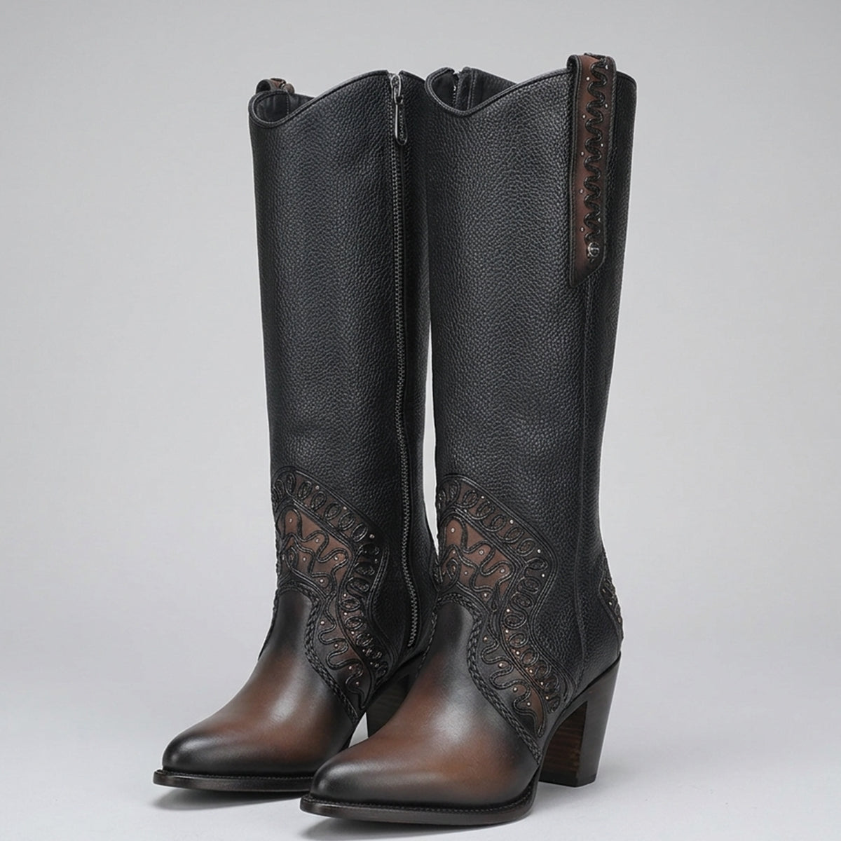 A pair of Cuadra tall brown leather boots with brown leather detailing on the toes, heels, and decorative side panels, shown against a neutral gray background.