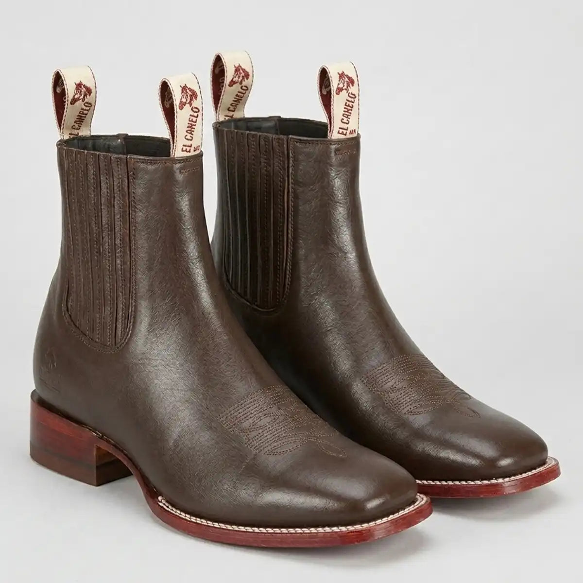 Pair of the Botín El Canelo Fronterizo dark brown caisson leather Western ankle boots with elastic side gores and logo pull tabs.