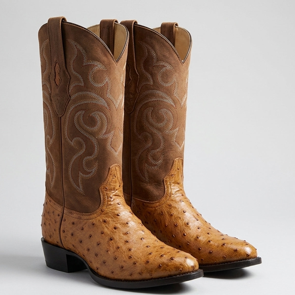 Los Altos men's amber tan ostrich leather round toe western boots featuring white western embroidery on the shaft and a black block heel, shown against a light gray background.
