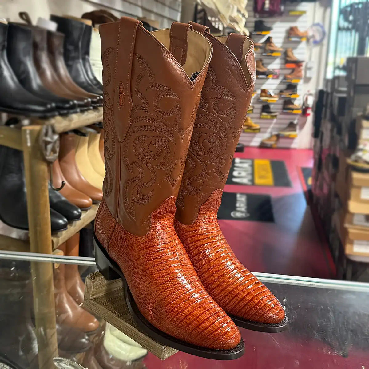 Pair of Los Altos Men's exotic cognac lizard skin cowboy boots with a classic round toe and matching embroidered leather shaft with a western store background.