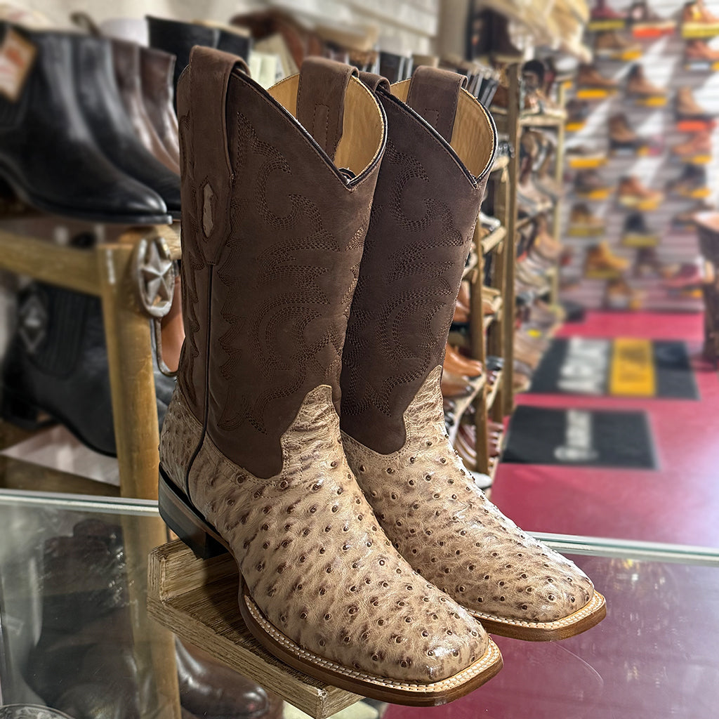 High-angle retail display shot of the Los Altos full quill ostrich boots placed on a glass counter inside a Western wear store.