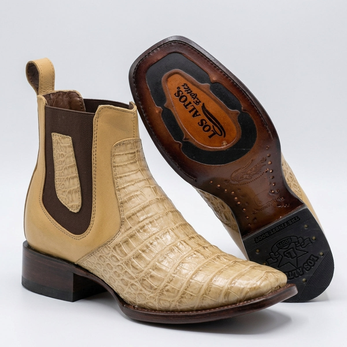 A pair of Los Altos boots western ankle boots, featuring a tan and beige alligator-leather upper with dark brown elastic side panels and a dark brown block heel. One boot is shown from the side, and the other is turned to display the branded brown leather insole.