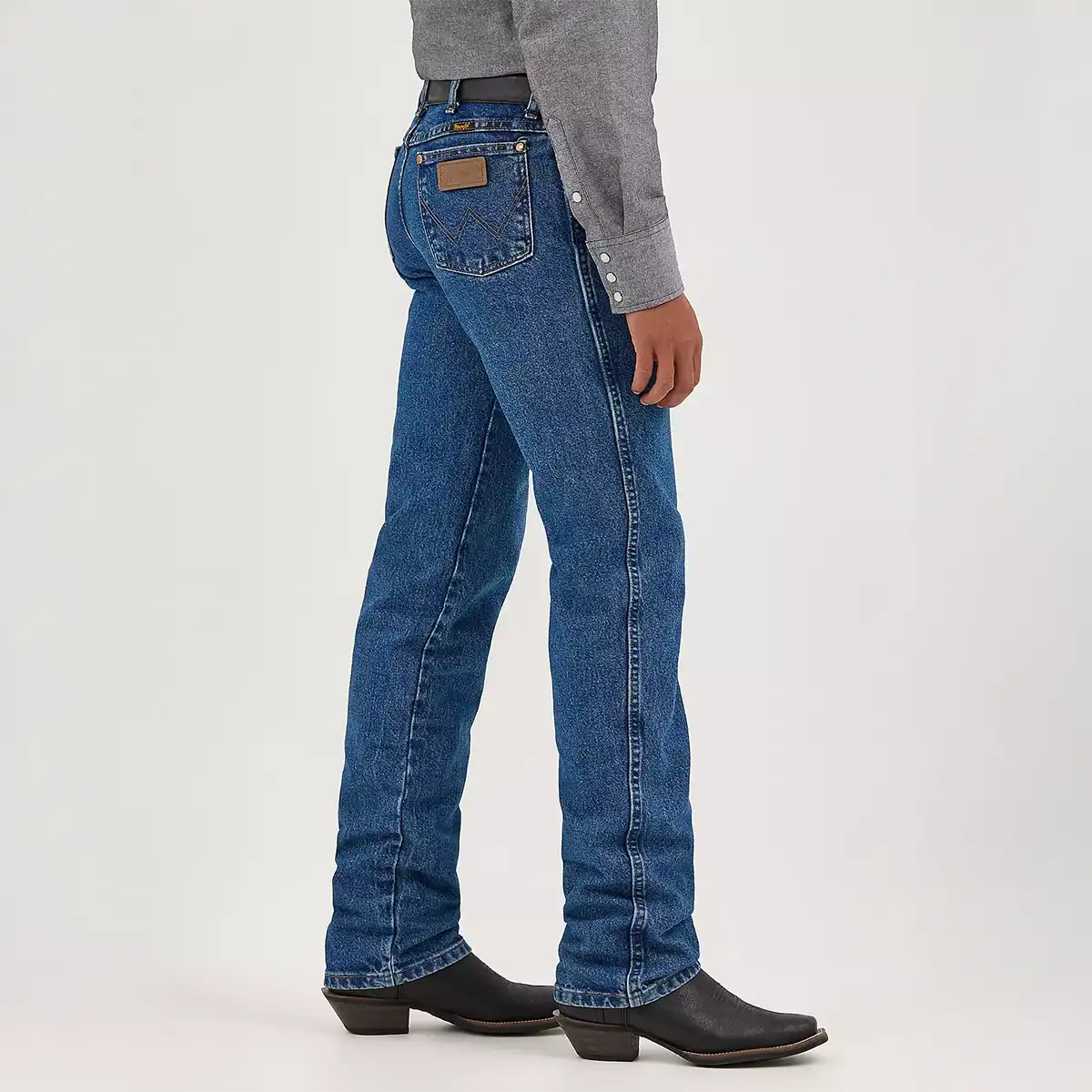 Side profile view of a man wearing Wrangler slim fit stonewashed jeans showing the high rise and tapered boot-cut leg.