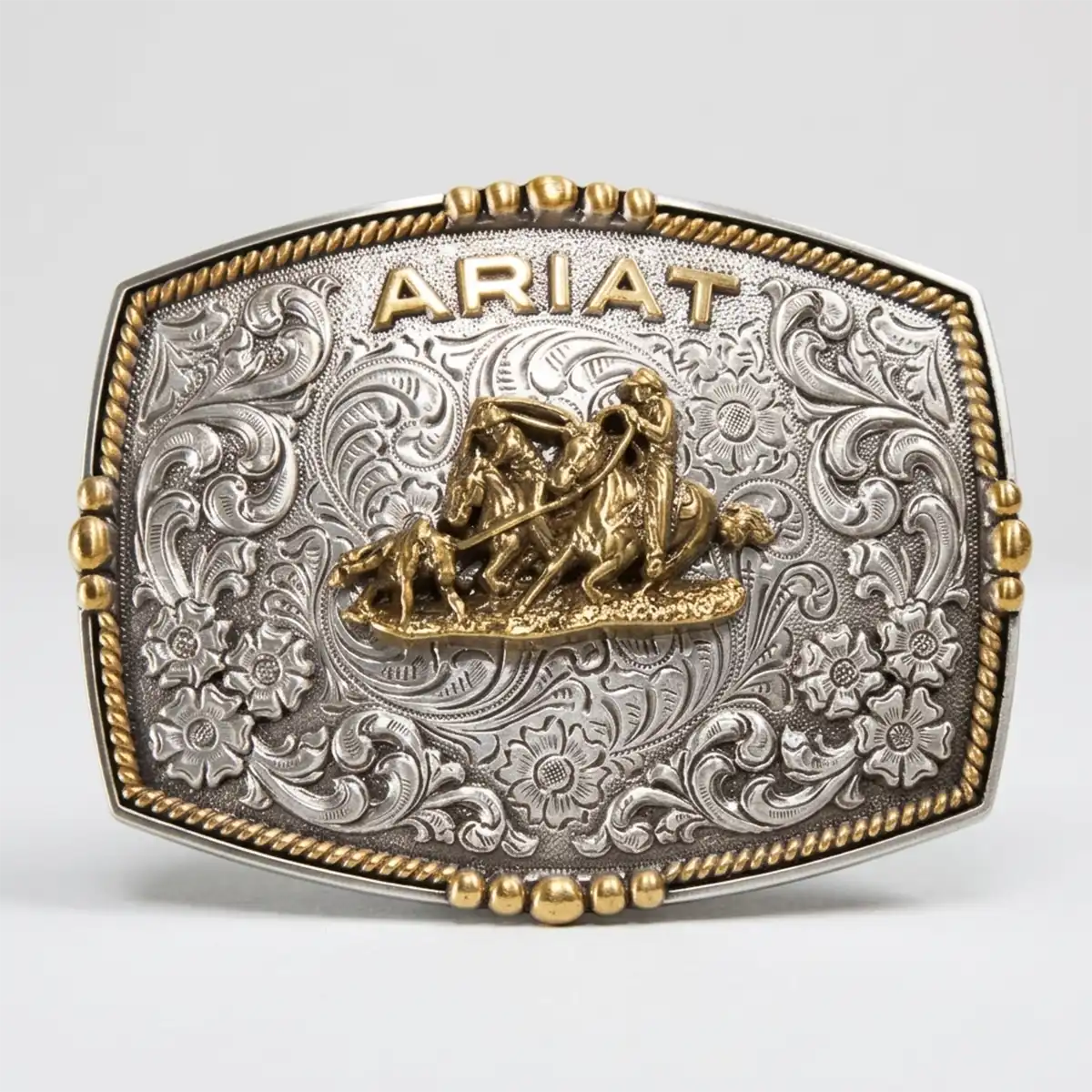 Ariat men's rectangle multi-finish belt buckle featuring an antique gold team roper motif, raised Ariat logo, and silver floral scrollwork.