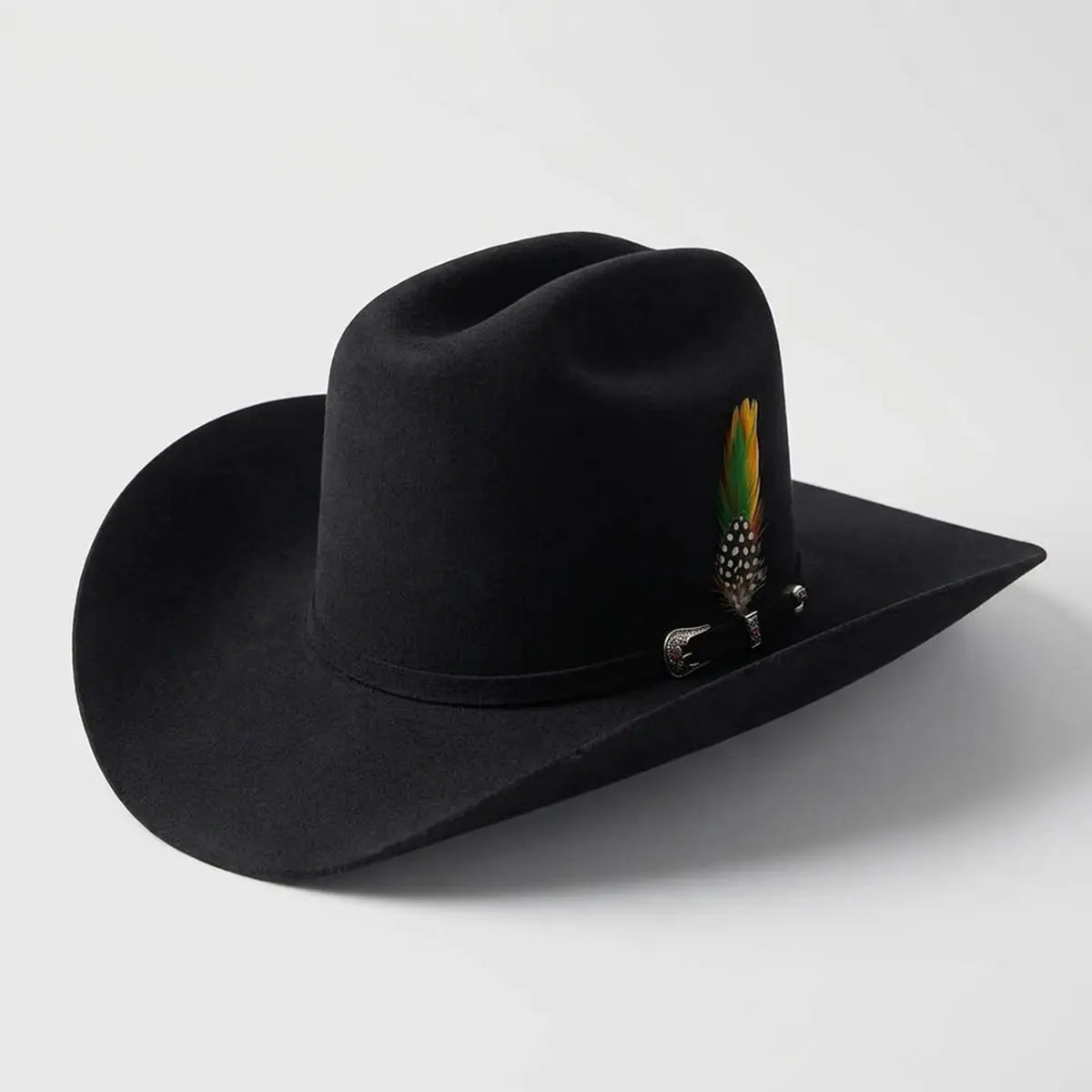 Three-quarter studio profile view of the Abolengo Rancheron 1000X jet black rabbit fur felt western hat displaying the Cattleman crown crease, silver buckle set, and colorful feather accent.
