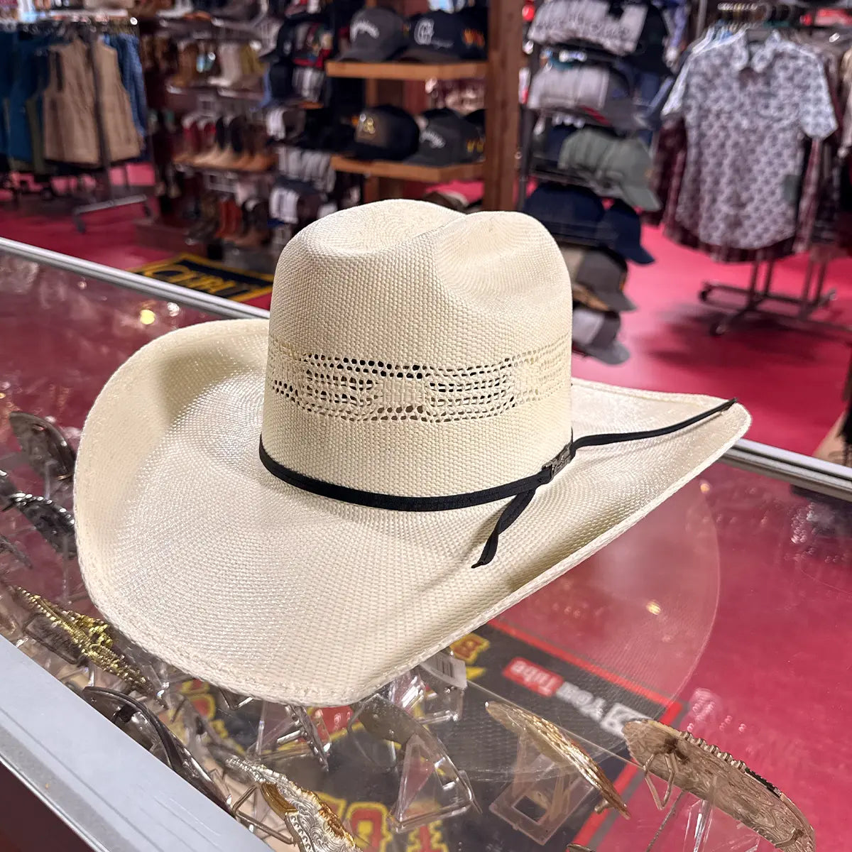 In-store glass display view of the American Hat Co. 657 Bangora straw hat highlighting the silver buckle accent on the black ribbon band.