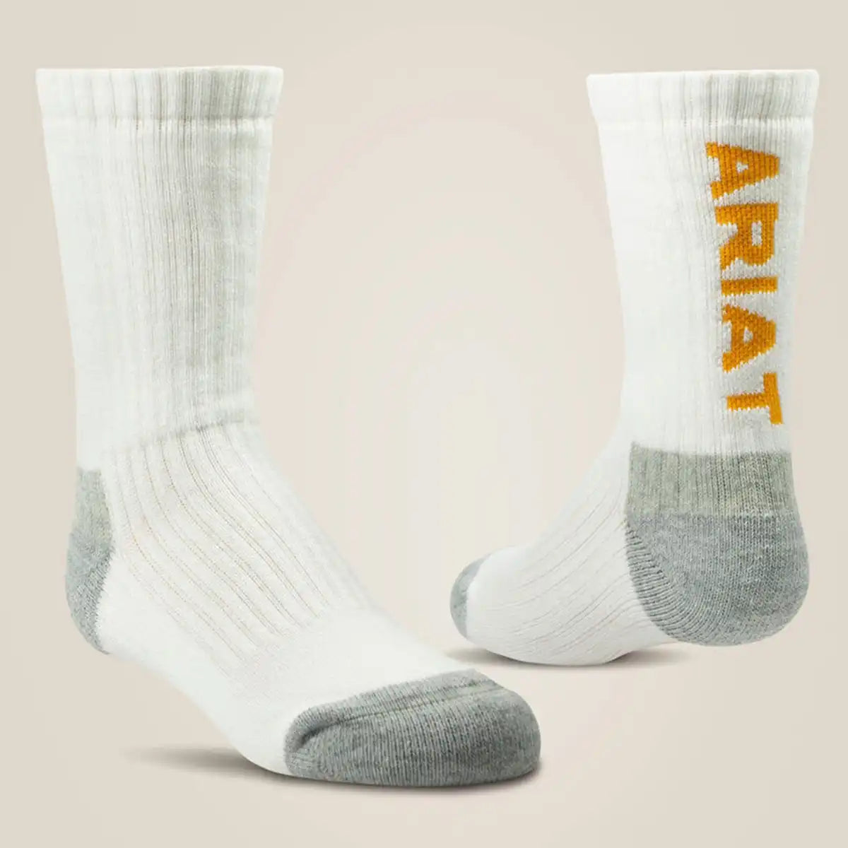 Pair of Ariat kids' white performance cotton crew socks showcasing gray heel/toe cushioning and vertical gold Ariat text logo along the upper ribbed shaft.