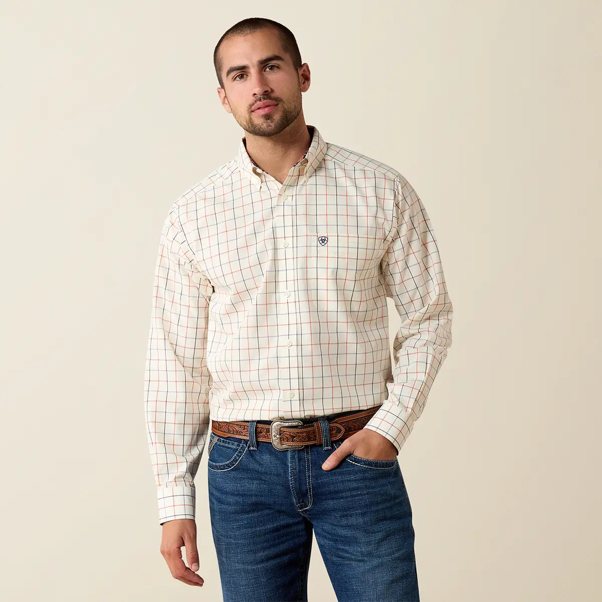 Half-body studio view of a male model wearing the Ariat Arctic Wolf windowpane plaid shirt tucked into dark blue jeans with a Western belt.