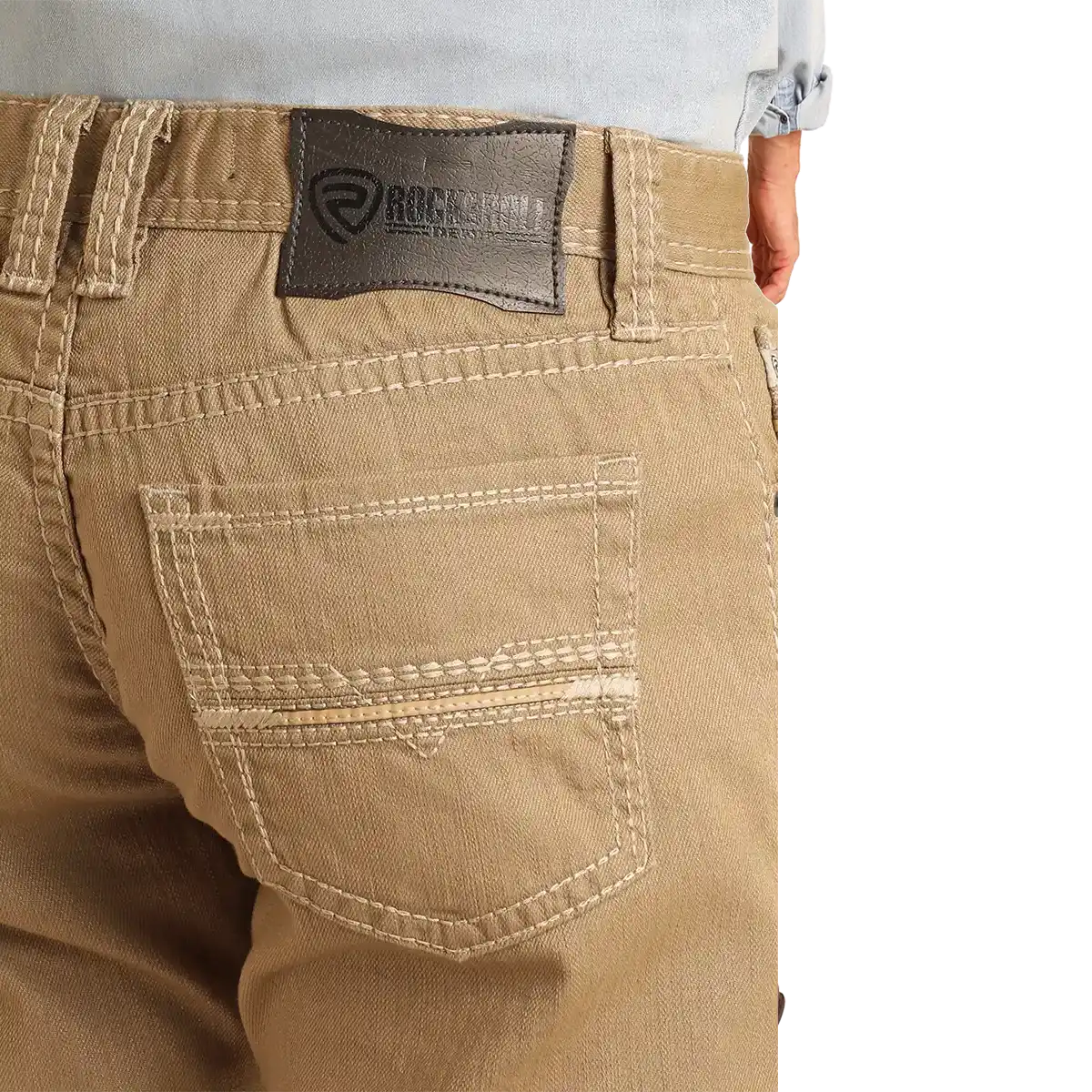 Close-up of the back waistband and pocket area of tan denim jeans, showing a Rockroll brand patch on the waistband and contrast stitching.