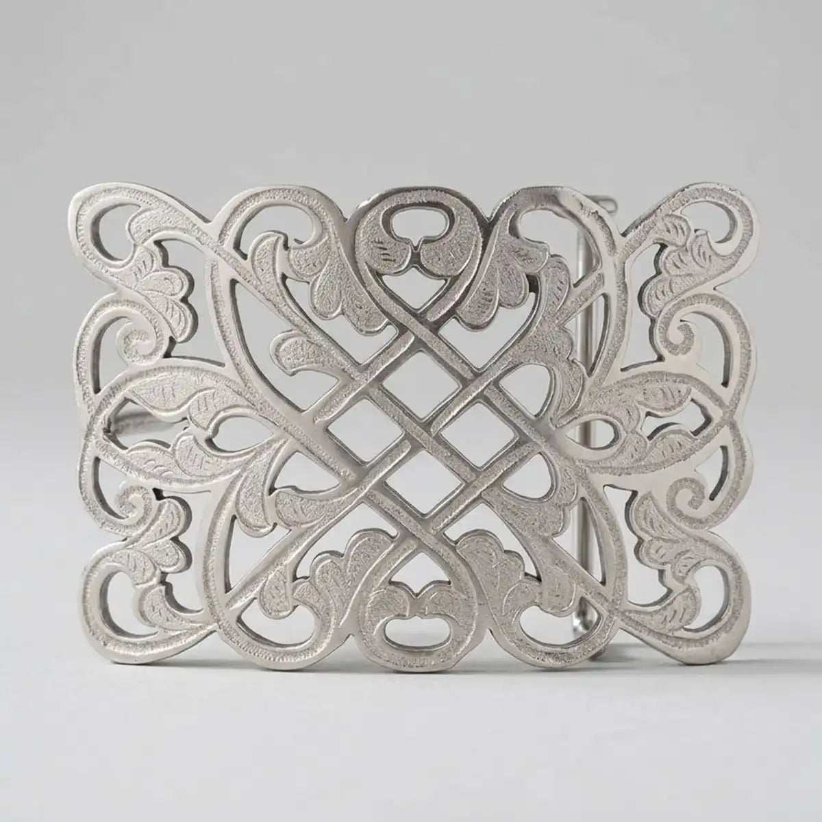 A silver-toned metal western belt buckle with an intricate openwork Celtic knot design, photographed against a neutral light gray background.